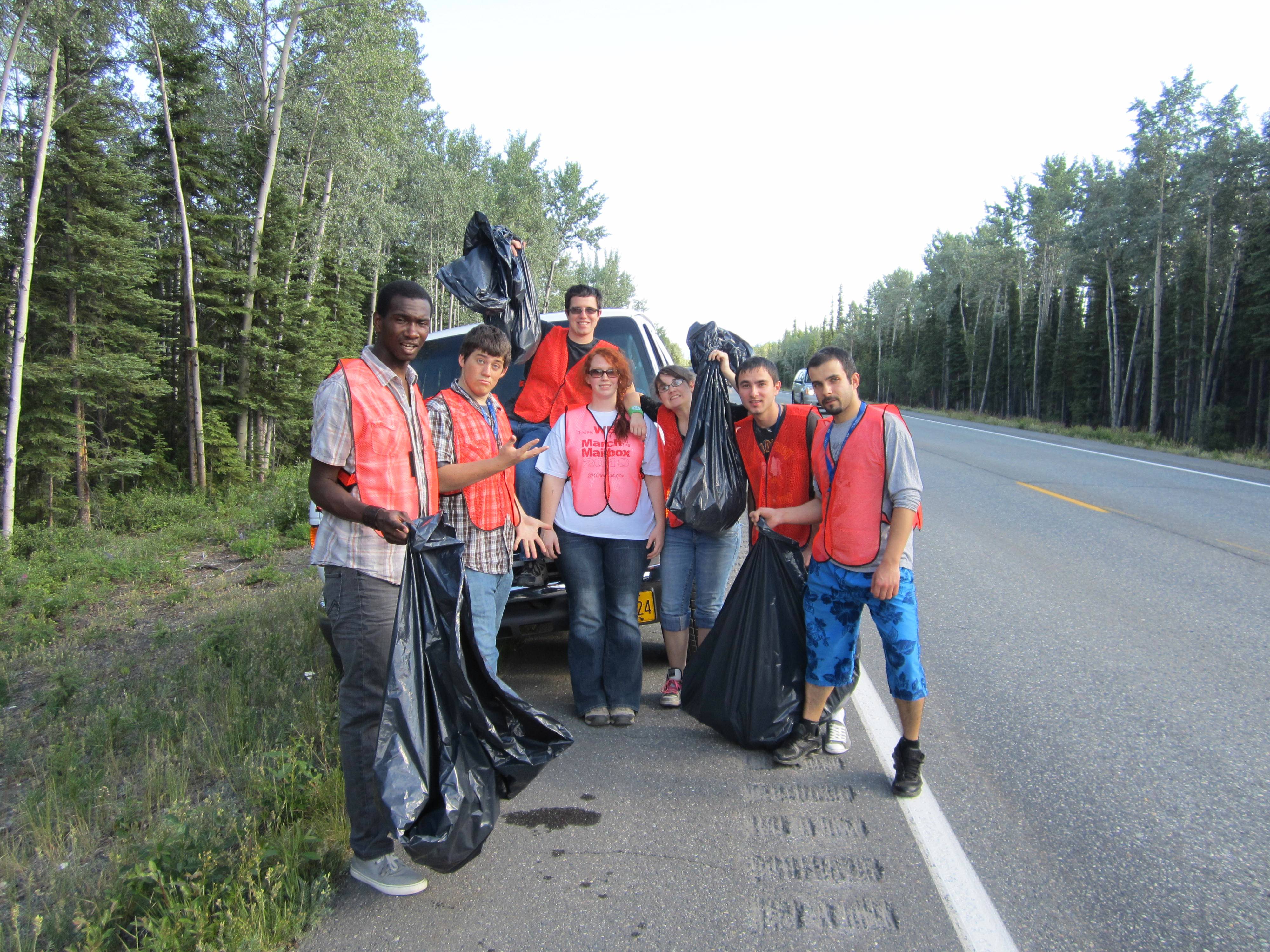 Princess Lodges employees wearing orange vests pose for a photo on the shoulder of the highway