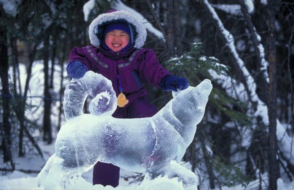 Fairbanks Ice Sculpture Young girl with a big smile touching a wolf ice sculpture