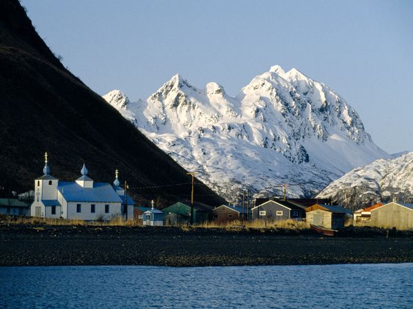 snow covered mountain behind a fishing village and russian church