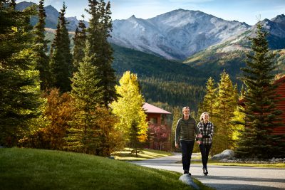 Couple walking the grounds on with fall foliage around at Kenai Princess Wilderness Lodge