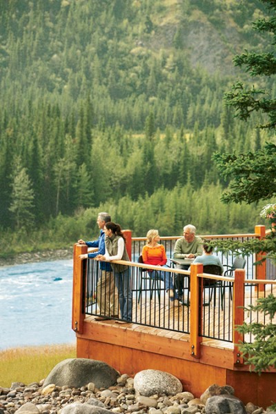 Guests on the deck overlooking the river at the Denali Princess Wilderness Lodge