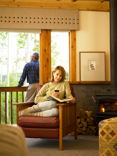 Woman reading and enjoying a glass of wine in a guestroom at the Kenai Princess Lodge