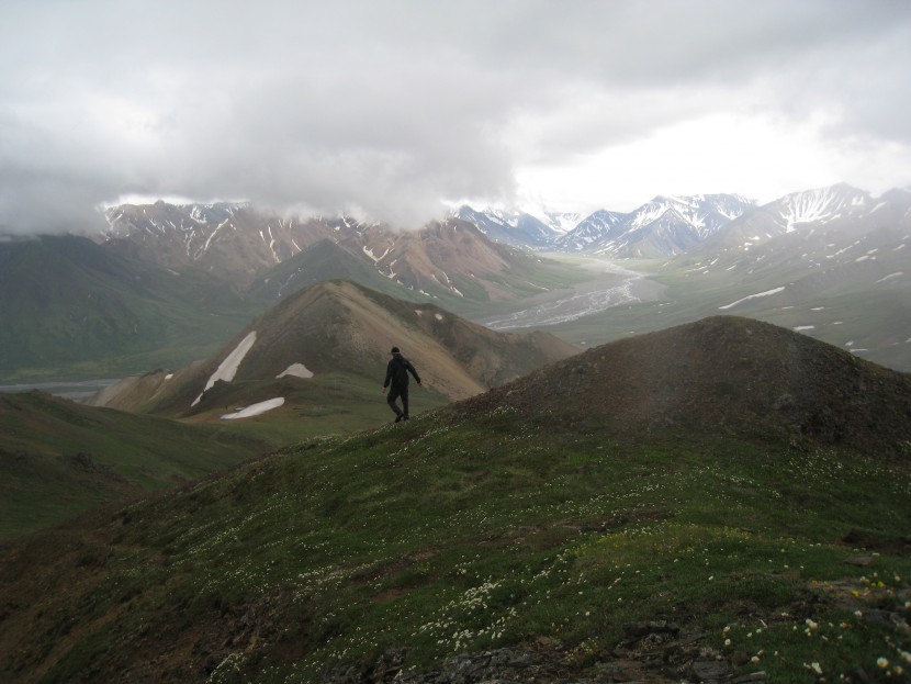 A hiker looks out on a mountain range