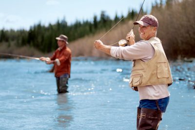 Two fisherman stand in the river