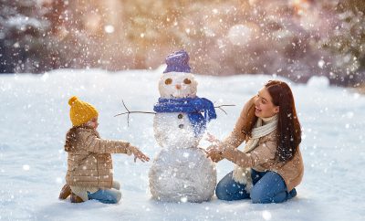 A mother and child build a snowman