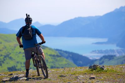 A cyclist pauses to take in the view of a lake at the base of mountains