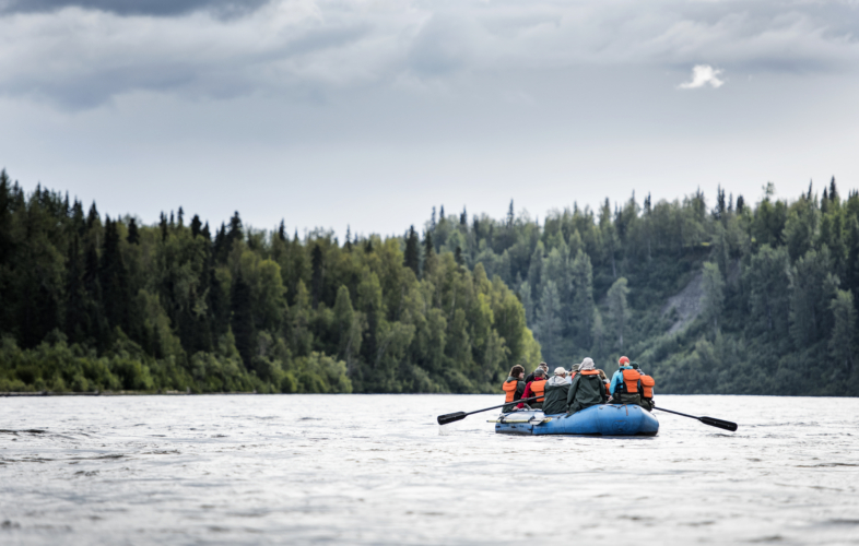 Blue raft full of visitors paddling in the river