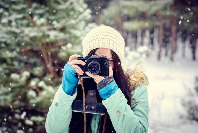 A woman looks through a camera, ready to take a picture.